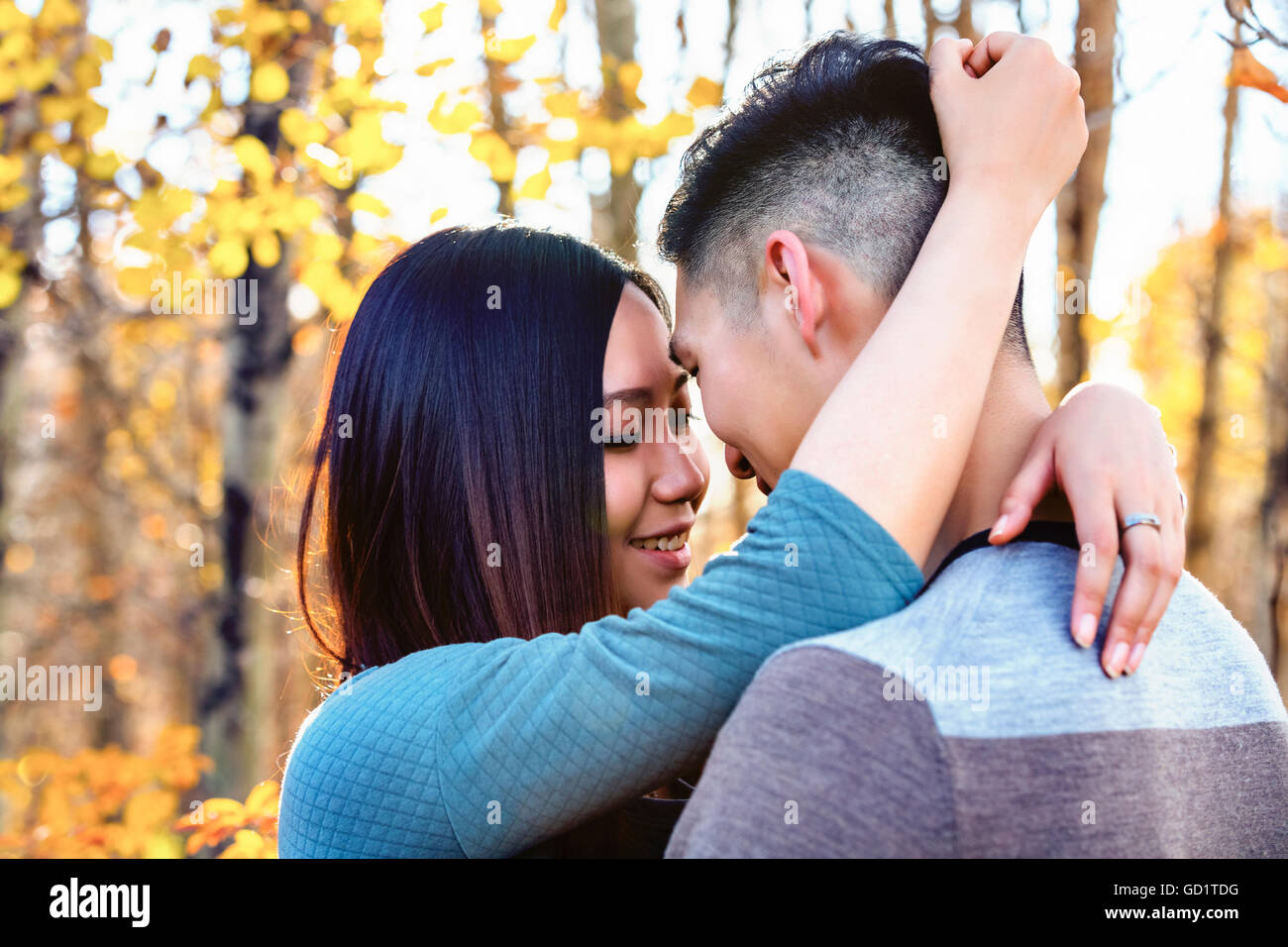 Una giovane coppia asiatica godendo Di Un tempo romantico insieme all'aperto in Un Parco in autunno e abbracciandosi nel calore della luce del sole... Foto Stock