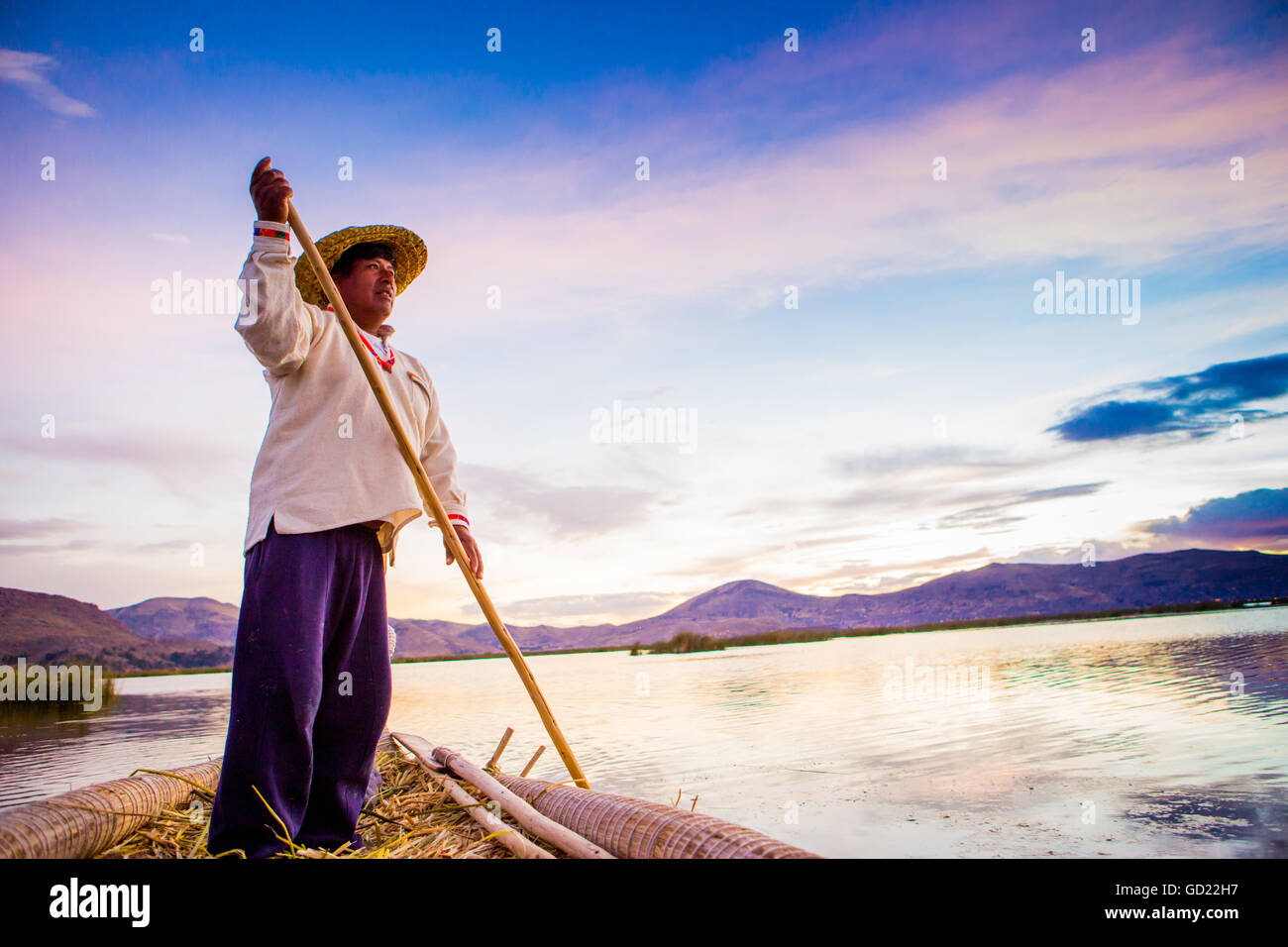 Il quechua uomo remare una barca sull'erba flottante isole di Uros, il lago Titicaca, Perù, Sud America Foto Stock