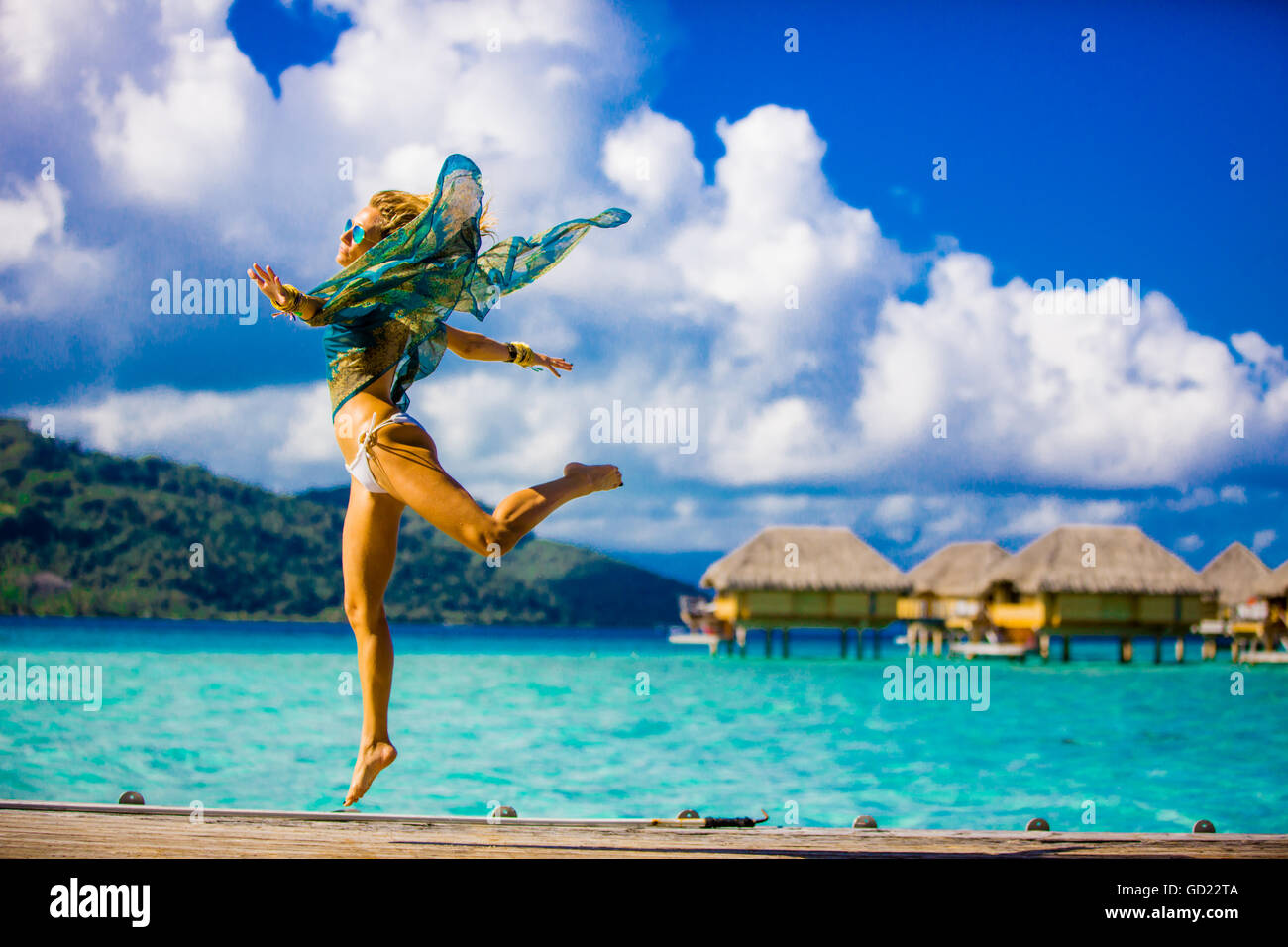 Ragazza jumping davanti al bungalow Overwater, dimora Le Taha'a Resort, Tahiti, Polinesia francese, South Pacific Pacific Foto Stock