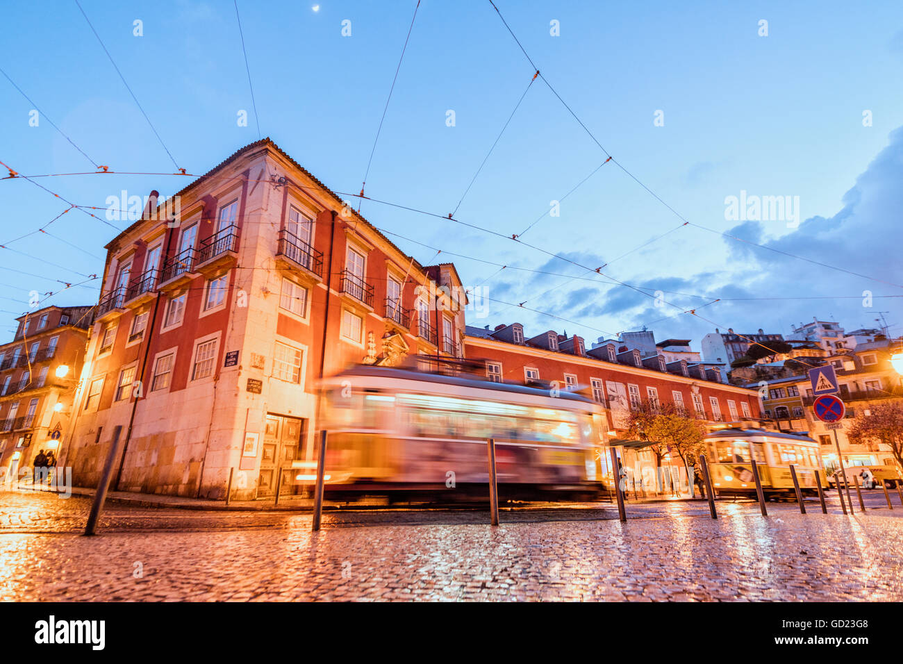 Luci della città in tipica architettura e vecchie strade al tramonto mentre il tram 28 procede, Alfama, Lisbona, Portogallo, Europa Foto Stock
