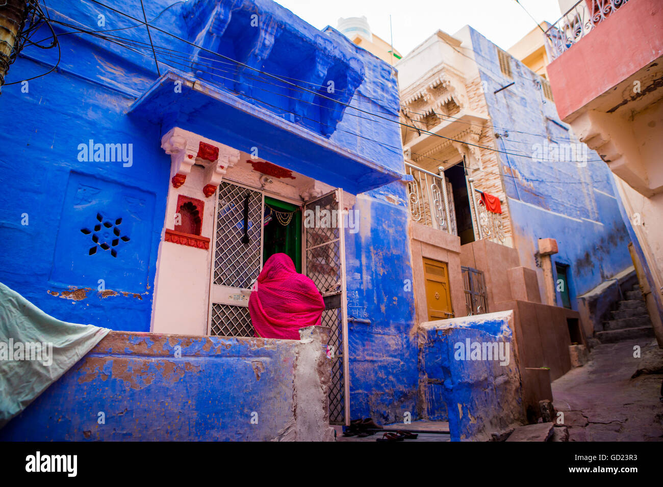 Donna in piedi di fronte alla sua casa blu in Jodhpur la città blu, Rajasthan, India, Asia Foto Stock