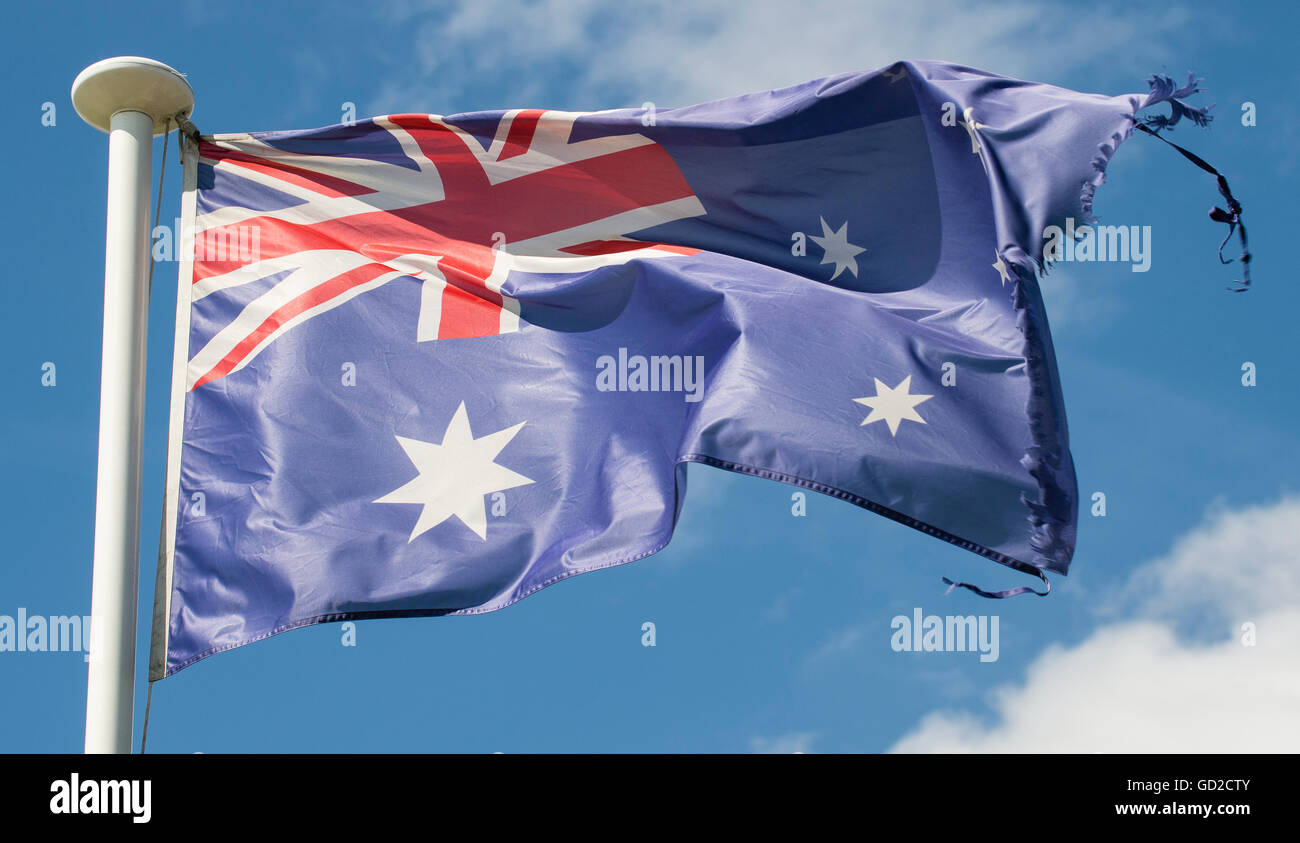 Bandiera australiana soffiando nel vento sulla bandiera bianca in pole con cielo blu e bianchi e soffici nuvole in background Foto Stock