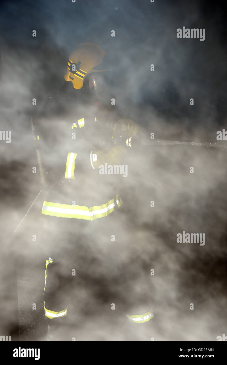 Servizio antincendio. Regno Unito. La Gran Bretagna. Vigile del fuoco in piena di fumo camera Foto Stock