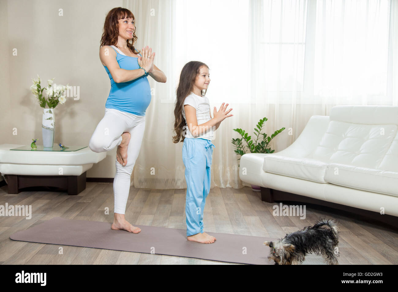 Famiglia uno stile di vita sano concetto. Gravidanza Yoga e fitness. Giovani yoga in gravidanza mamma lavora con bambina in vita Foto Stock