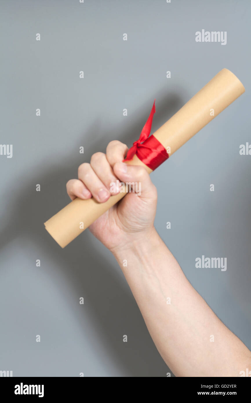 Diploma con un nastro rosso in mano su sfondo grigio Foto Stock