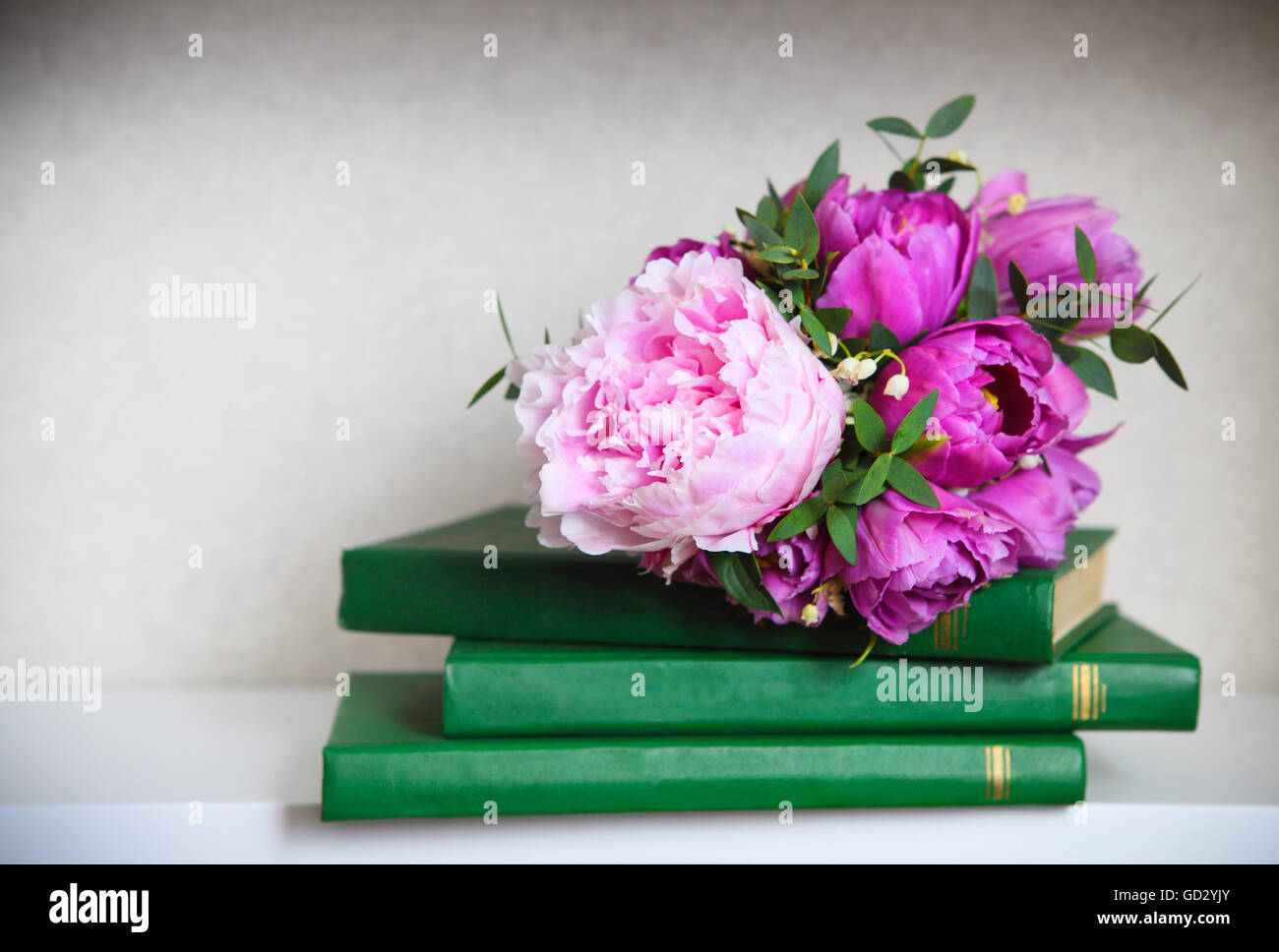 Bouquet di nozze di un rosa peonie, tulipani e il giglio della valle sui libri verdi Foto Stock