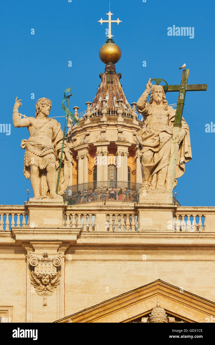 Le statue di San Giovanni Battista (sinistra) e Gesù tenendo una croce sopra la facciata della Basilica di San Pietro Roma Lazio Italia Europa Foto Stock