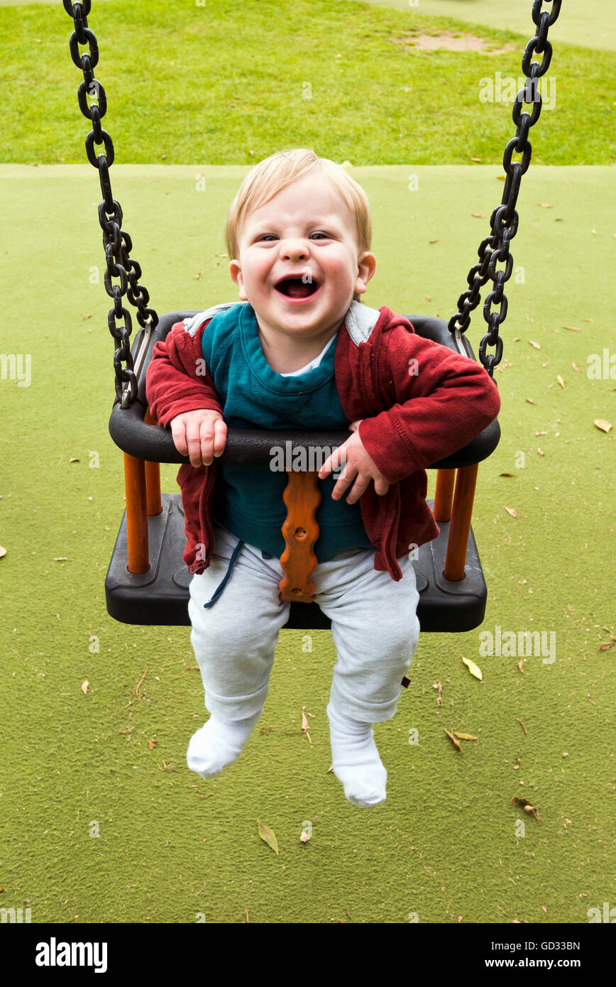 Ragazzo giovane ridere su uno swing Foto Stock