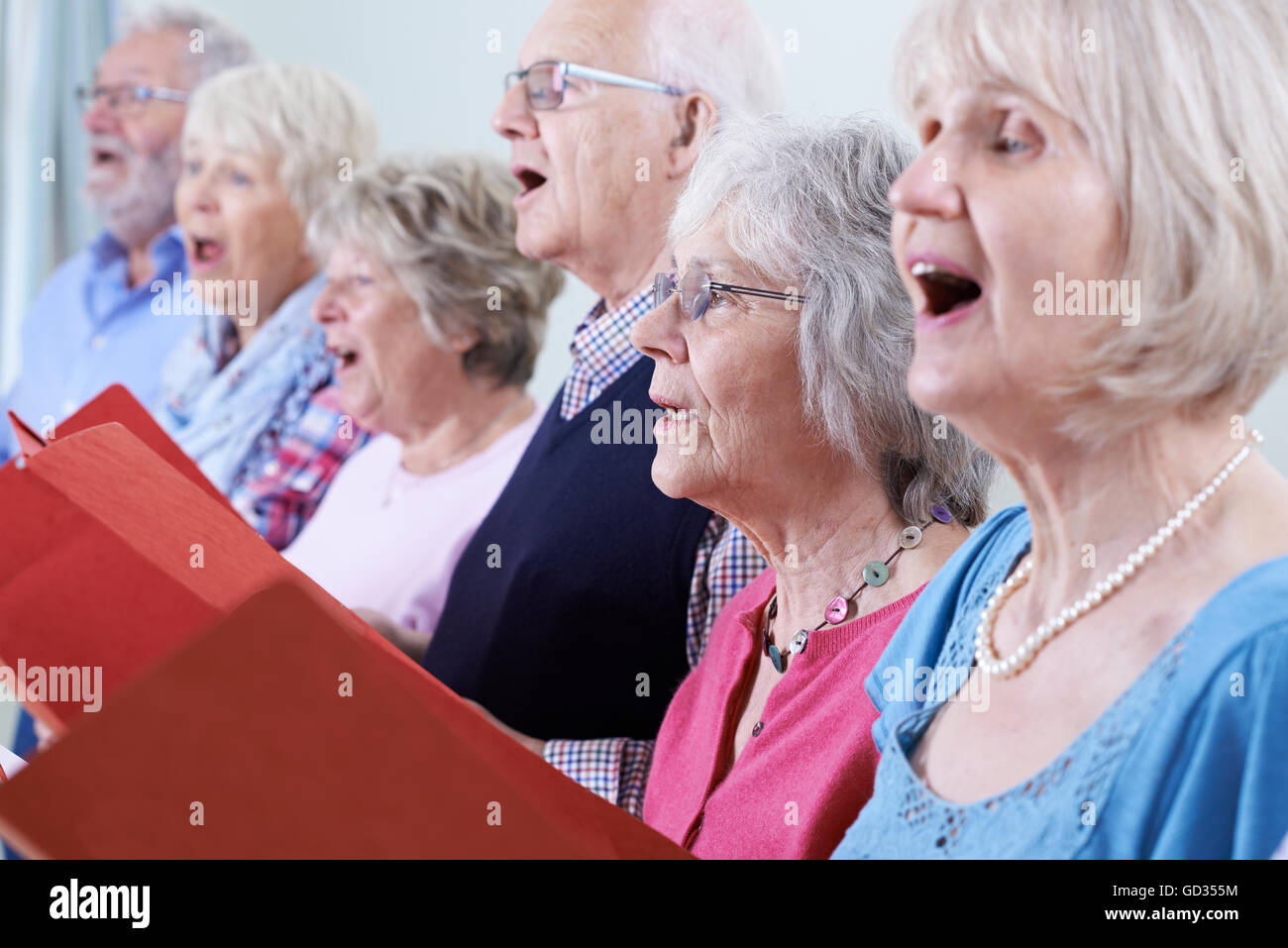 Gruppo di anziani a cantare in coro insieme Foto Stock