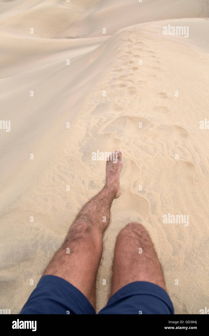 Le gambe di un uomo che cammina e lasciando impronta del piede sulla sabbia Foto Stock