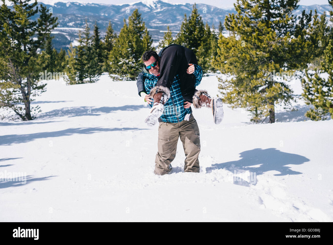 Un uomo nella neve profonda che porta una persona sulle sue spalle in un vigile del fuoco di sollevamento del. Foto Stock