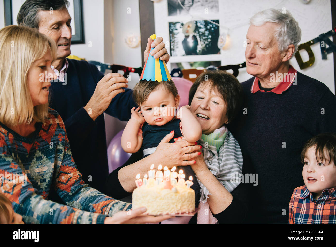 Una famiglia riunita per celebrare un anno di vecchia ragazza della festa di compleanno. Una torta con un sacco di candele. Foto Stock