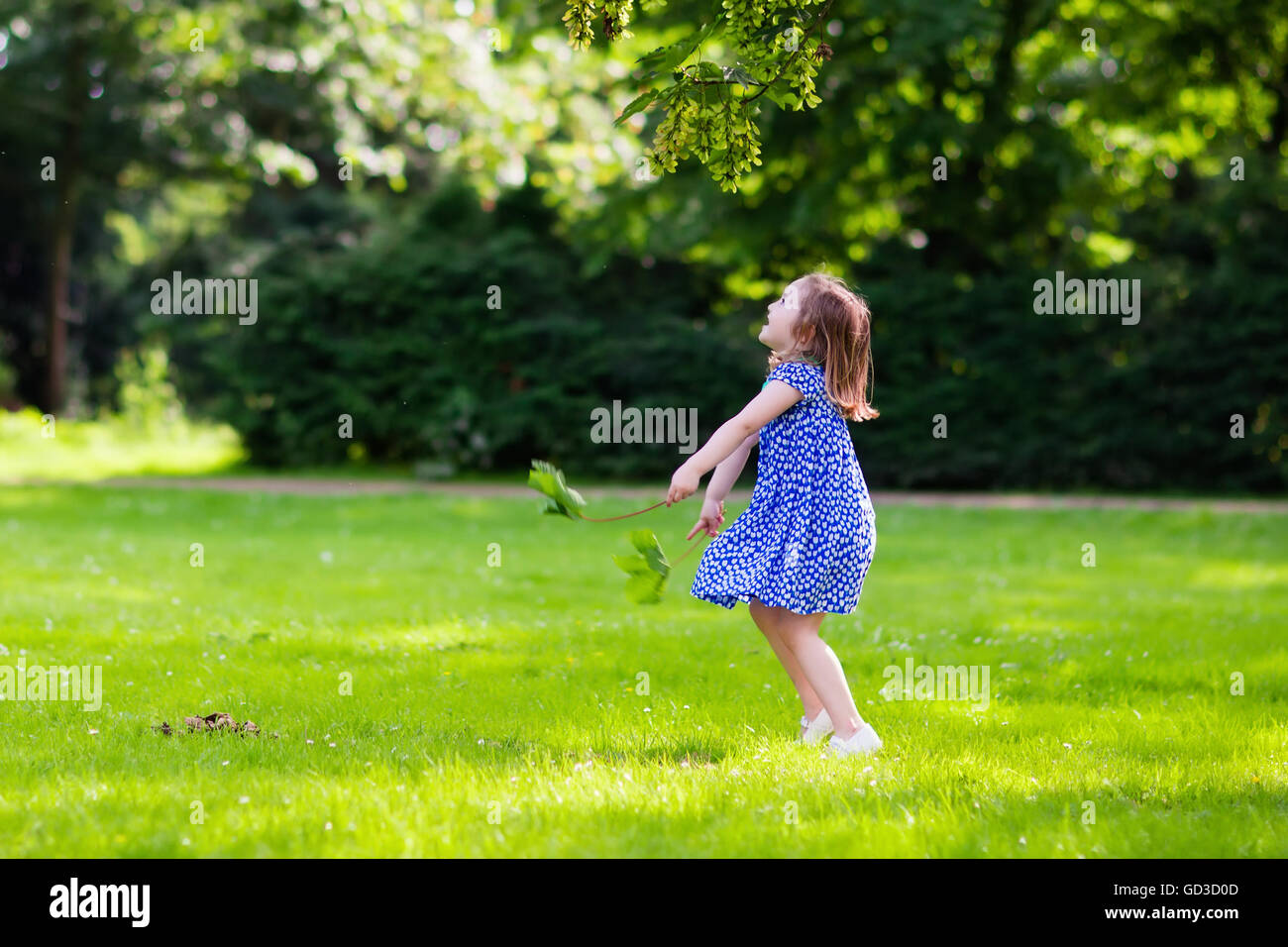 Carino bambina giocando nella soleggiata d'estate il parco. Bambino raccolta di foglie di acero. Il Toddler kid correre e saltare in una foresta. Foto Stock