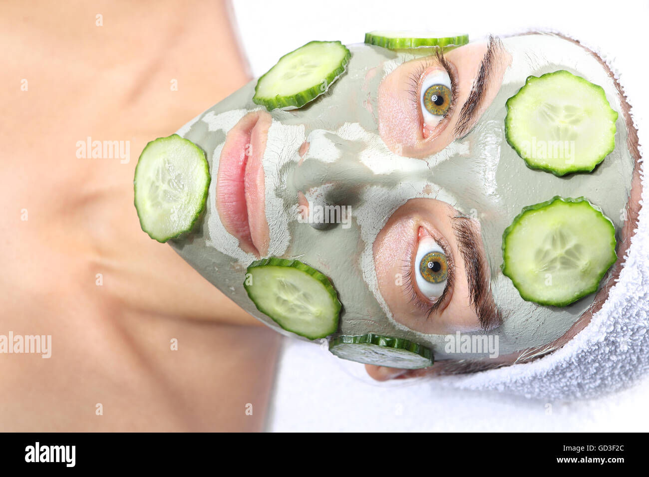 La donna si rilassa in maschera con argilla verde e il cetriolo. Foto Stock