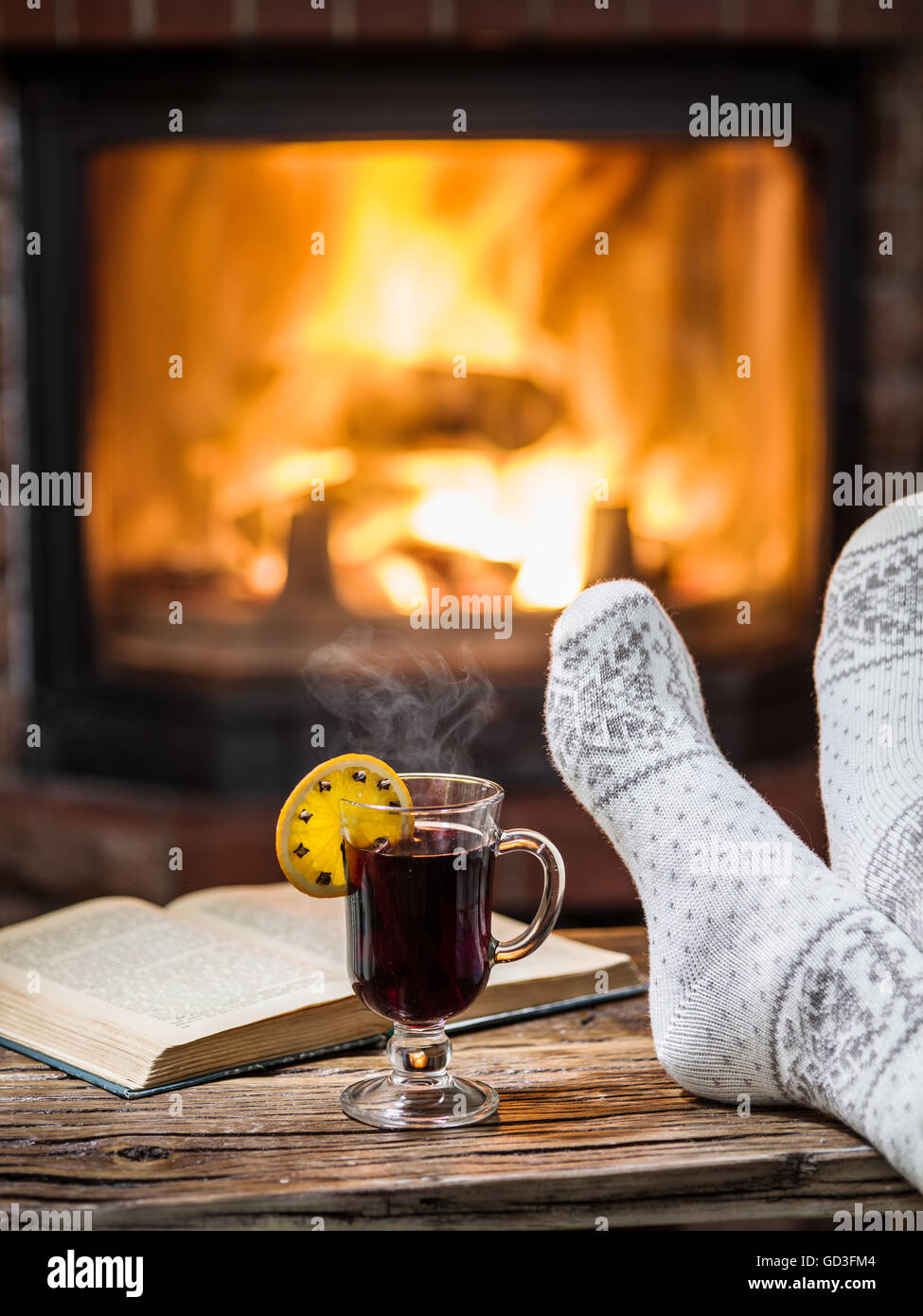 Riscaldamento e rilassarsi vicino al camino. Donna piedi vicino alla tazza di vino caldo nella parte anteriore del fuoco. Foto Stock