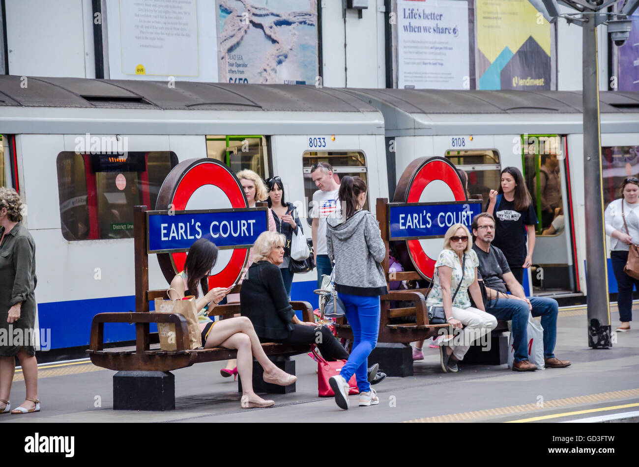 I passeggeri seduti sui banchi alla stazione della metropolitana di Earl's Court mentre si attende per il loro treno. Foto Stock