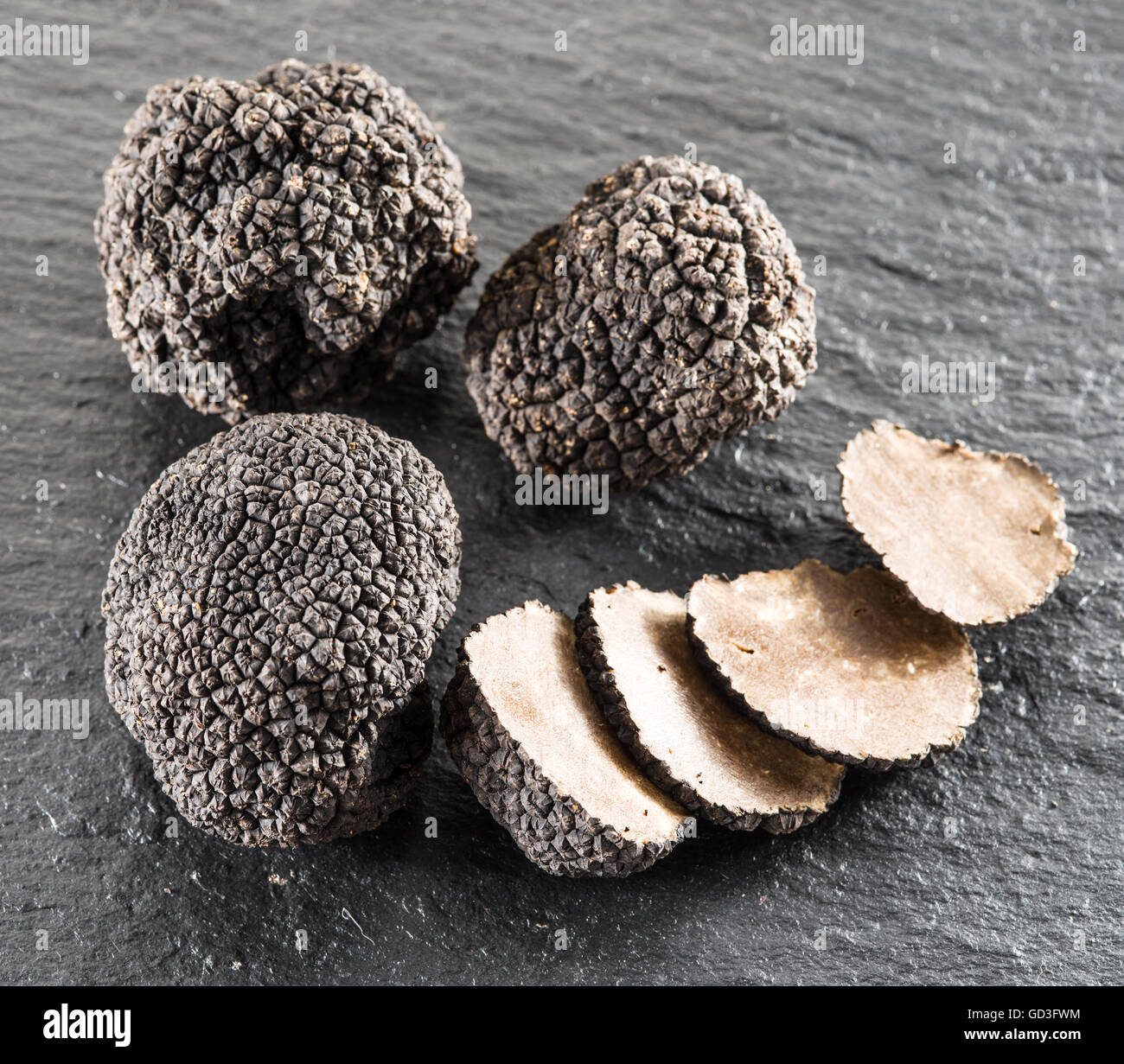 Tartufo nero e fettine di tartufo sulla scheda di grafite. Foto Stock