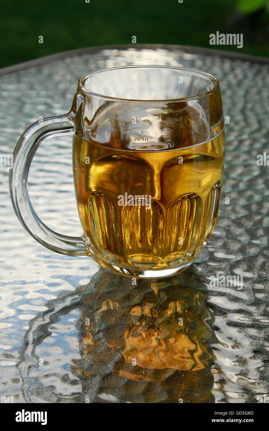 Un boccale di birra con birra ambrata su un tavolo di vetro Foto Stock