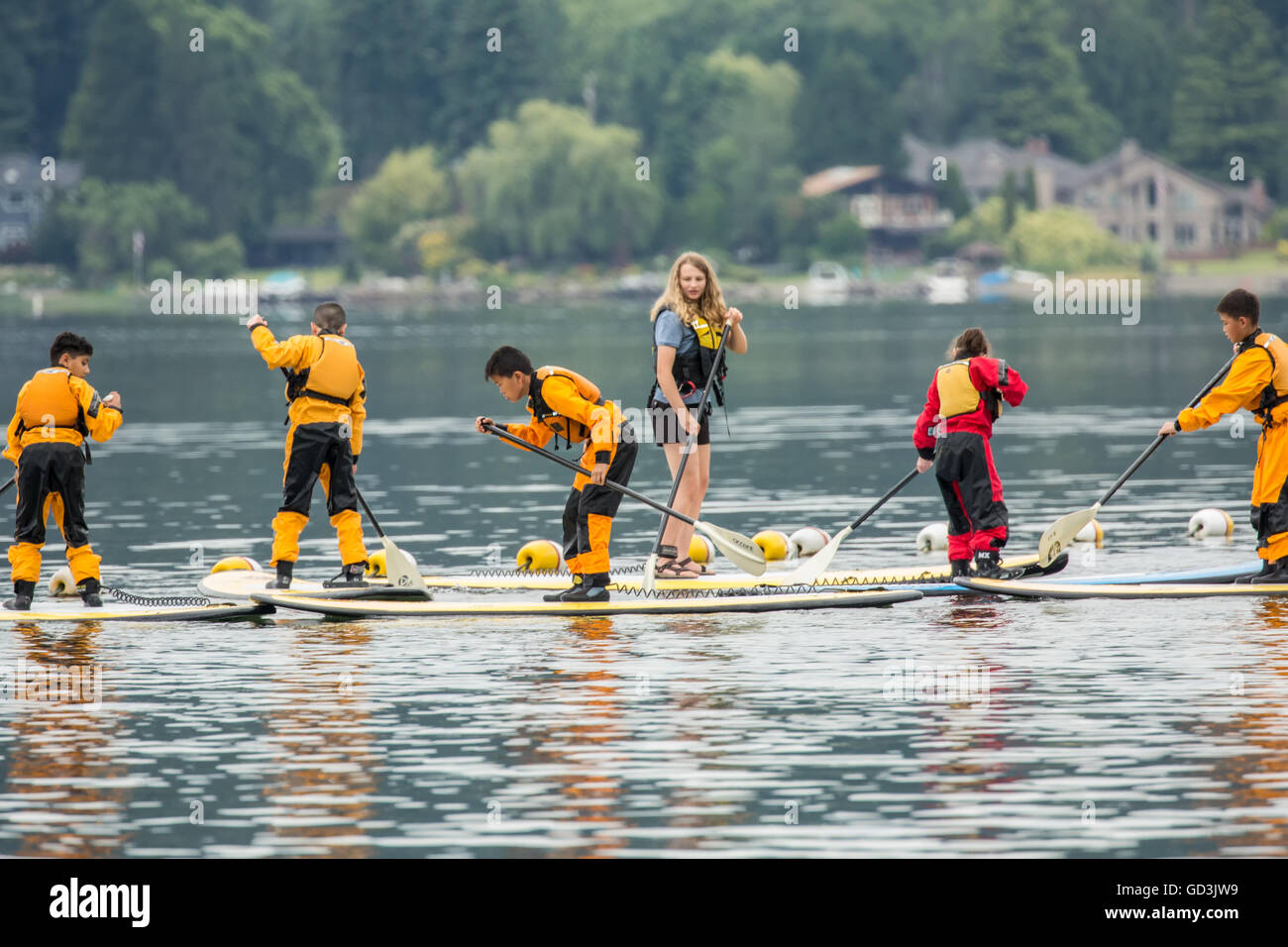 Donna insegnamento pre-adolescenti e adolescenti come paddleboard al Lago Sammamish State Park, Issaquah, Washington Foto Stock