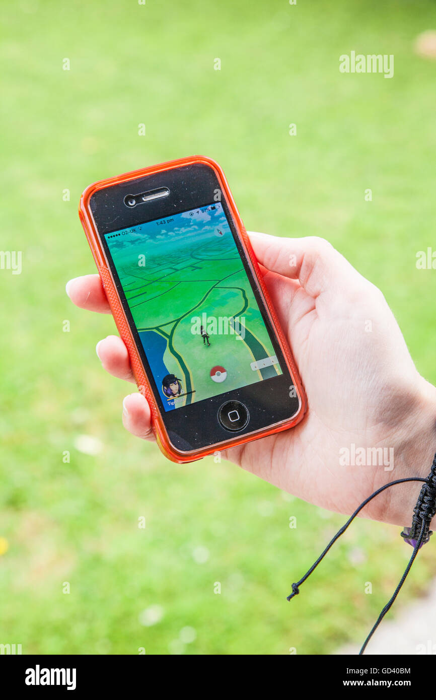 Un giovane persona utilizza un iPhone per giocare Pokémon andare, le ultime realtà aumentata mobile app Game per colpire tutto il mondo mercato app. Foto Stock