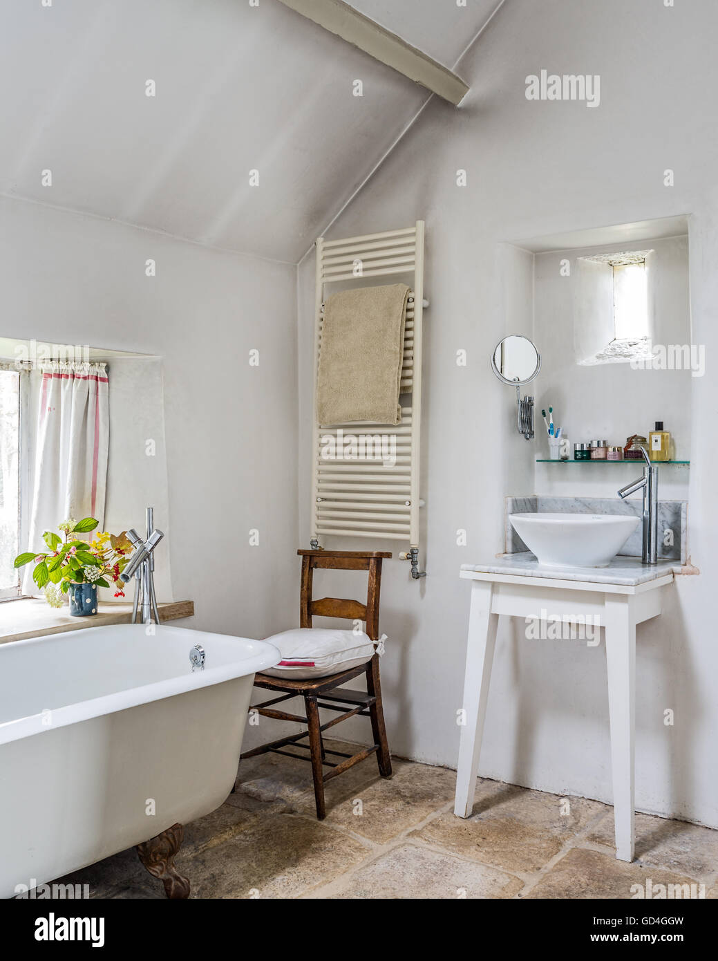 Radiatore termico e lavabo con vintage sedia in legno nella stanza da bagno Foto Stock