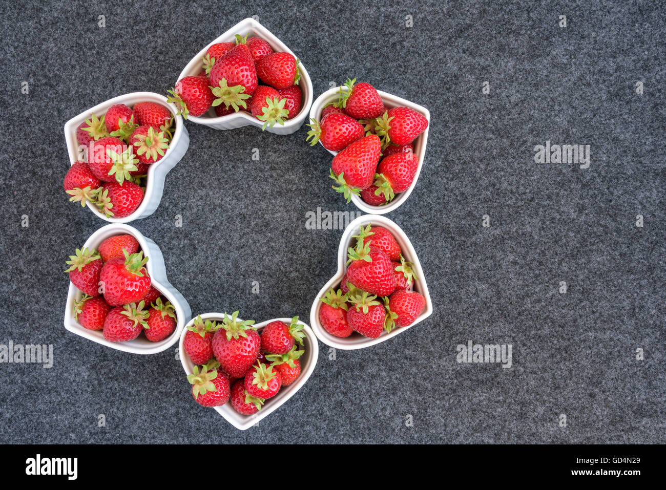 Raccolte fresche Fragole in bianco a forma di cuore, di bocce su sfondo grigio Foto Stock