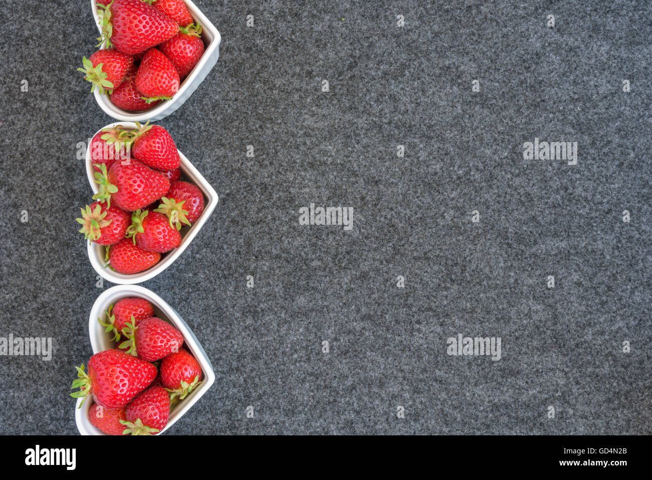 Raccolte fresche Fragole in bianco a forma di cuore, di bocce su sfondo grigio Foto Stock