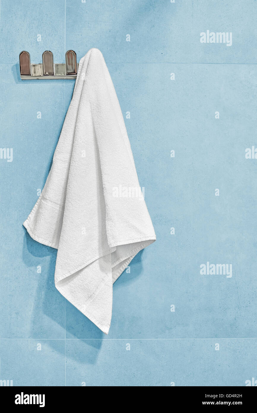 Asciugamano bianco appeso a una parete in bagno. Foto Stock