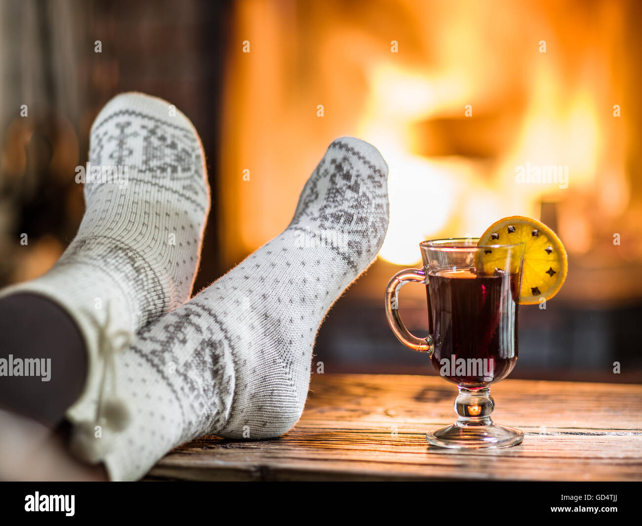 Riscaldamento e rilassarsi vicino al camino. Donna piedi vicino alla tazza di vino caldo nella parte anteriore del fuoco. Foto Stock