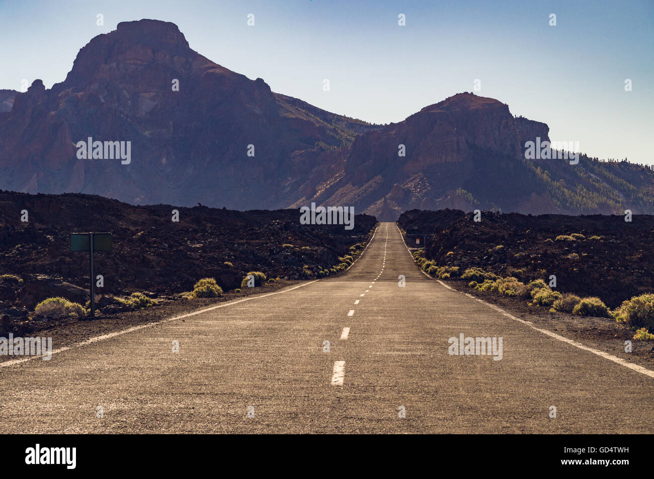 Vuoto diritte strade del deserto con montagne di haze sullo sfondo, Tenerife, Isole canarie, Spagna Foto Stock