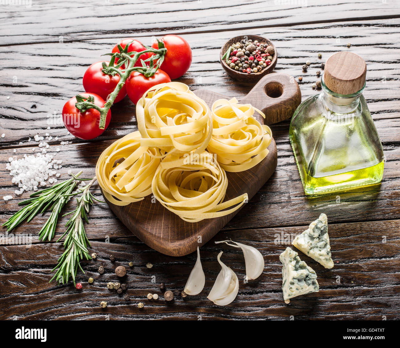 Ingredienti per la pasta. Cherry-pomodori, spaghetti, rosmarino e spezie sul tavolo di legno. Foto Stock
