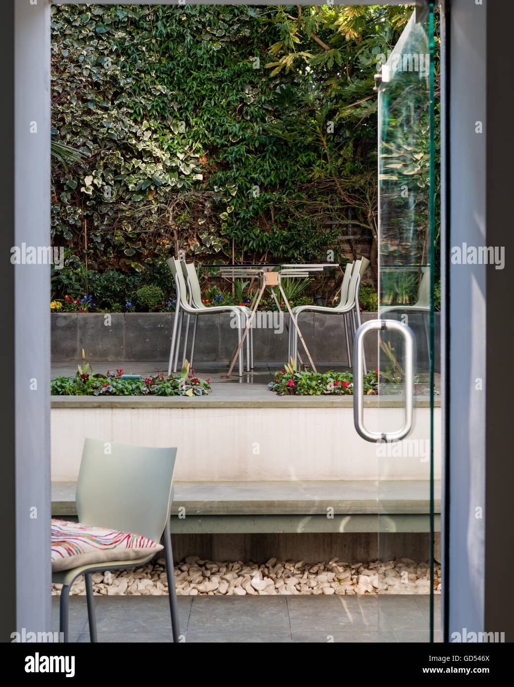 Visualizzare attraverso la porta aperta a sollevato area giardino con posti a sedere Foto Stock