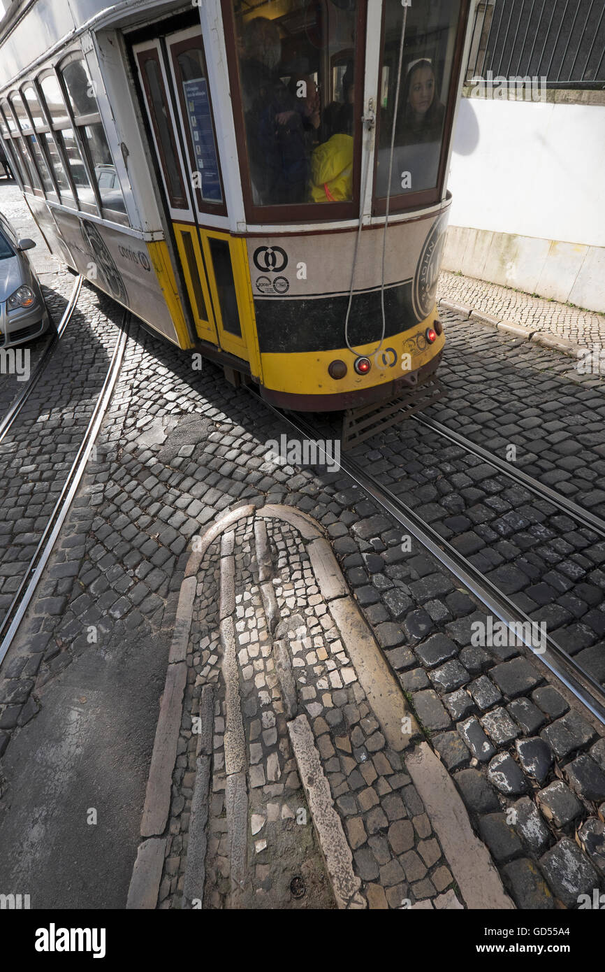 I tram a Lisbona con la luce del sole i modelli di colata e ombre sulla pavimentazione e i binari del tram Foto Stock