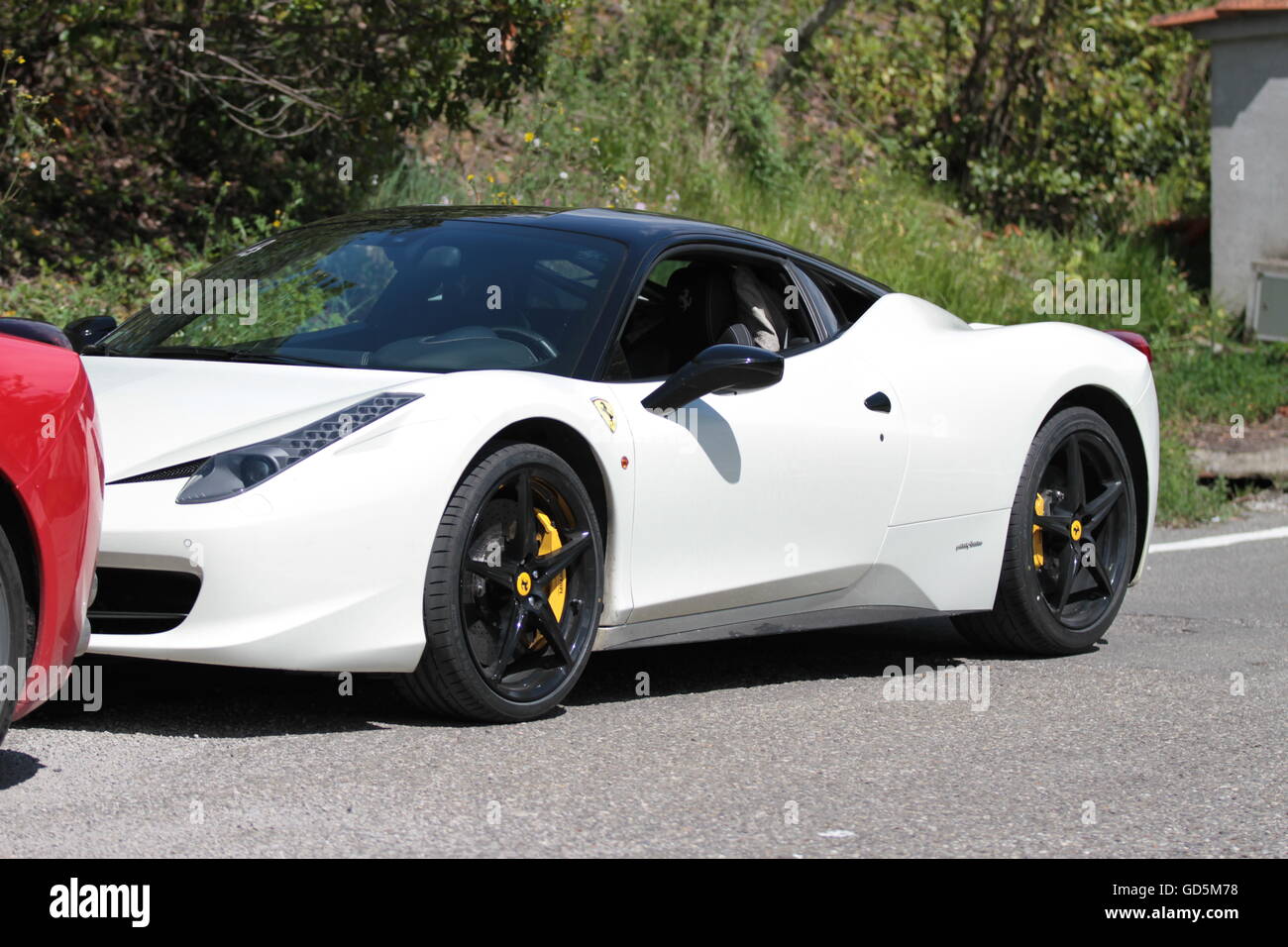 White Ferrari con ruote nere parcheggiata sul lato della strada in Toscana in una giornata di sole Foto Stock