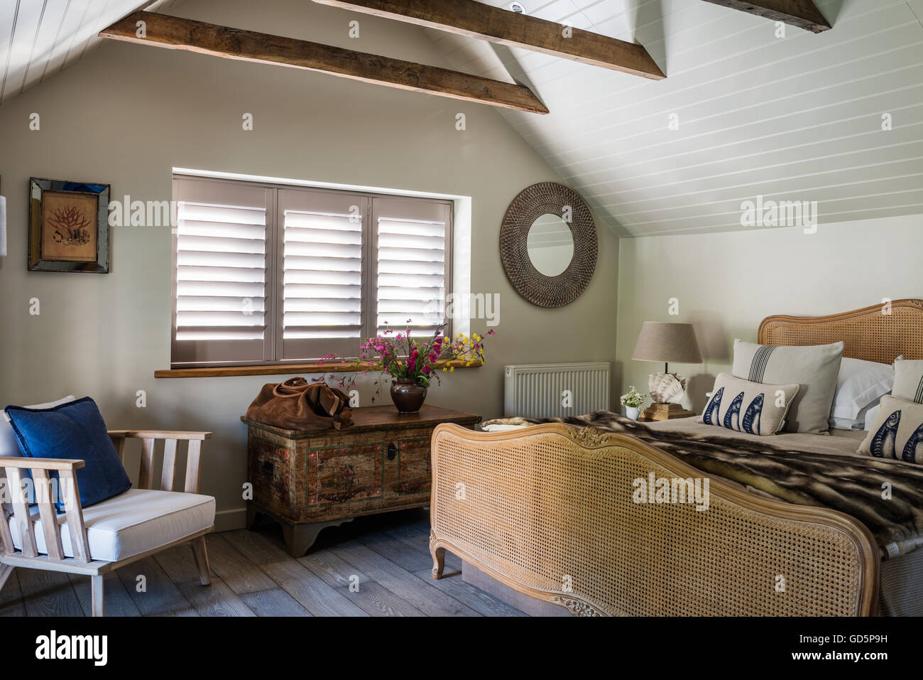 Persiane in stile piantagione bianco e soffitto in legno rivestimento in mansarda con camera da letto vintage di canna da zucchero francese letto. La sedia è da Pomax Foto Stock