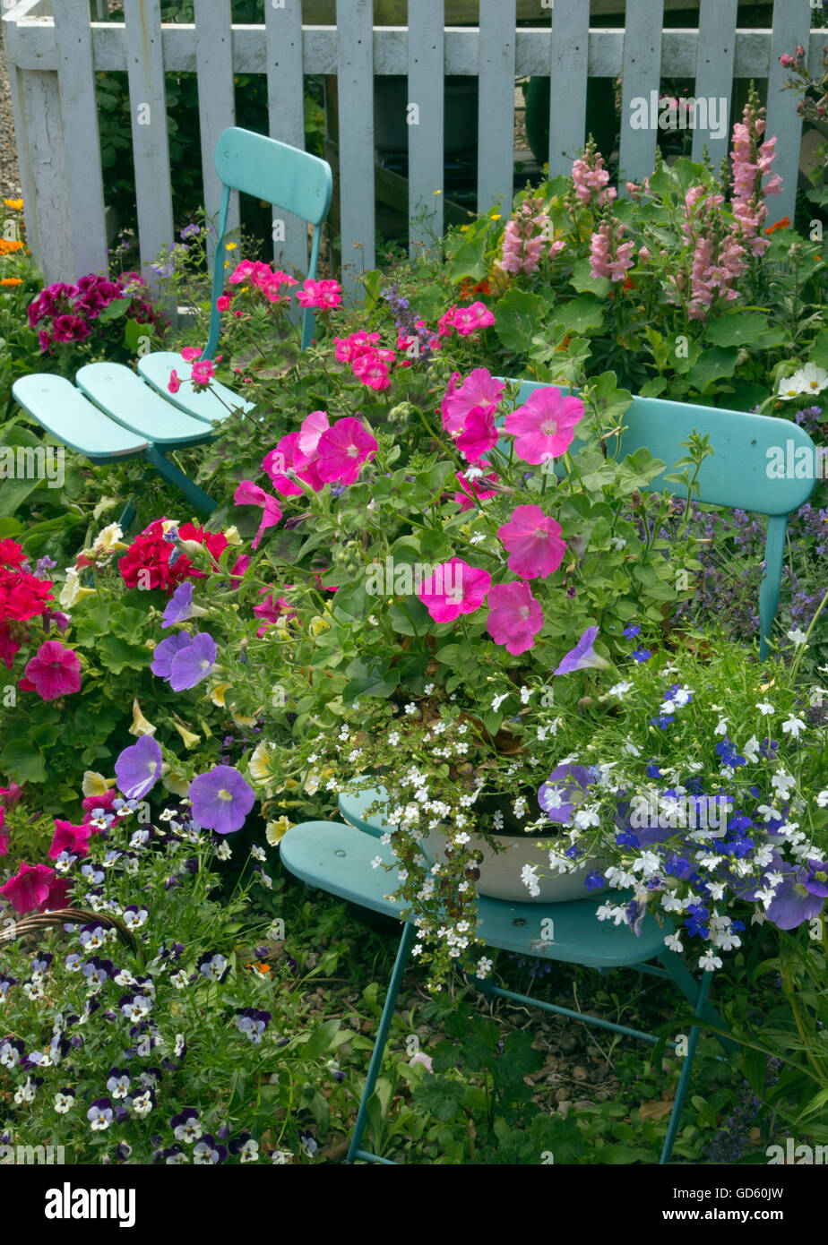 Grazioso giardino cottage con contenitori di fiori blu e tavolo e sedie Foto Stock
