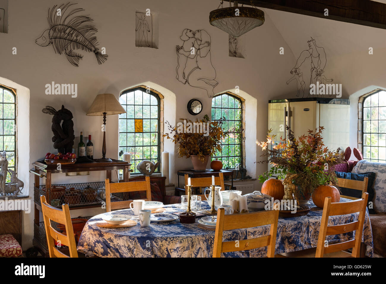 Sensazione rustica grande cucina sala da pranzo adornata con Sophie Ryder sculture di filo e mucchi di foglie di autunno. Le finestre sono Foto Stock