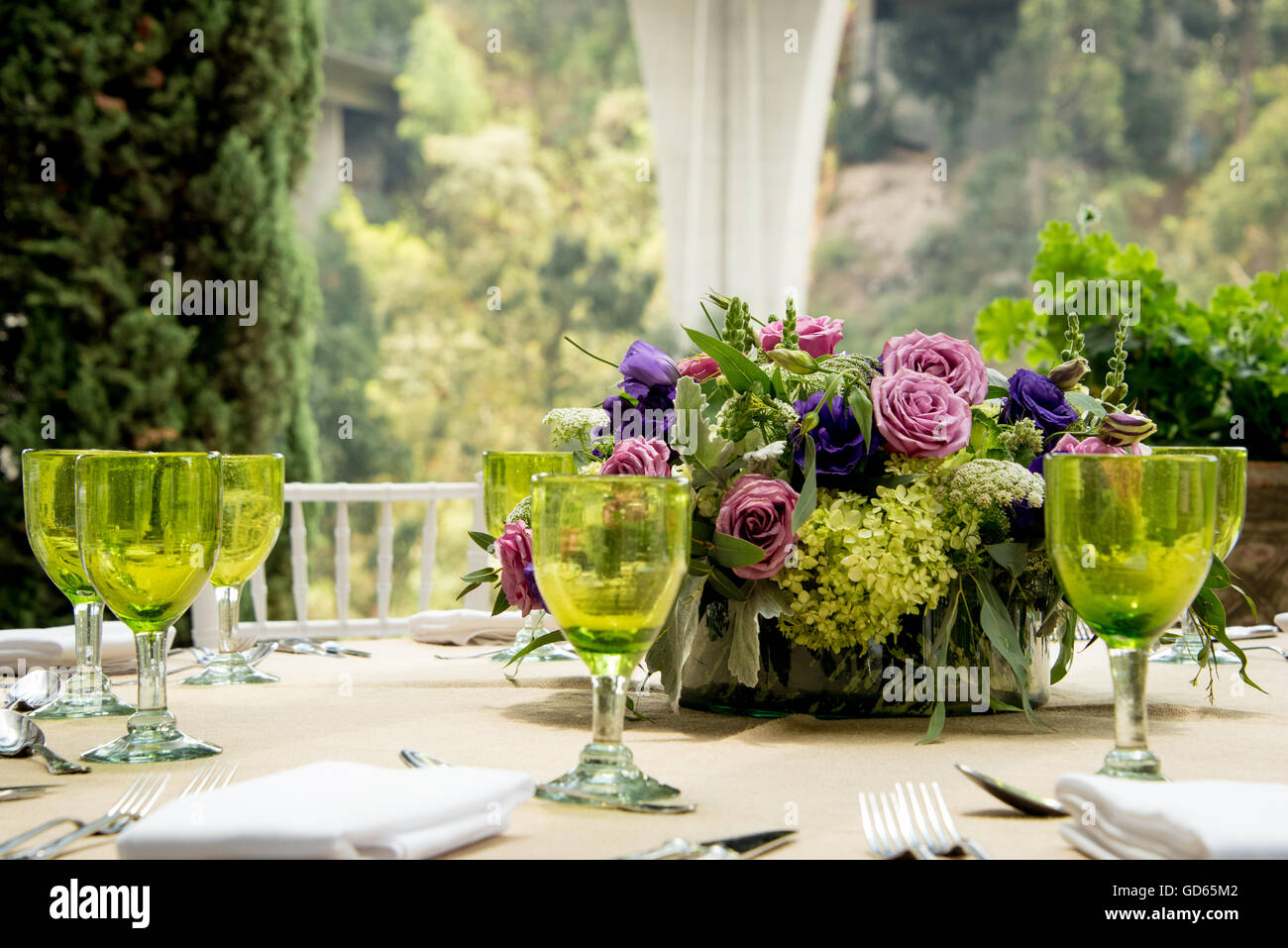 Tabella formale impostazione per un matrimonio con centrotavola floreali e colorati occhiali verdi davanti a una finestra di visualizzazione ampia overlookin Foto Stock