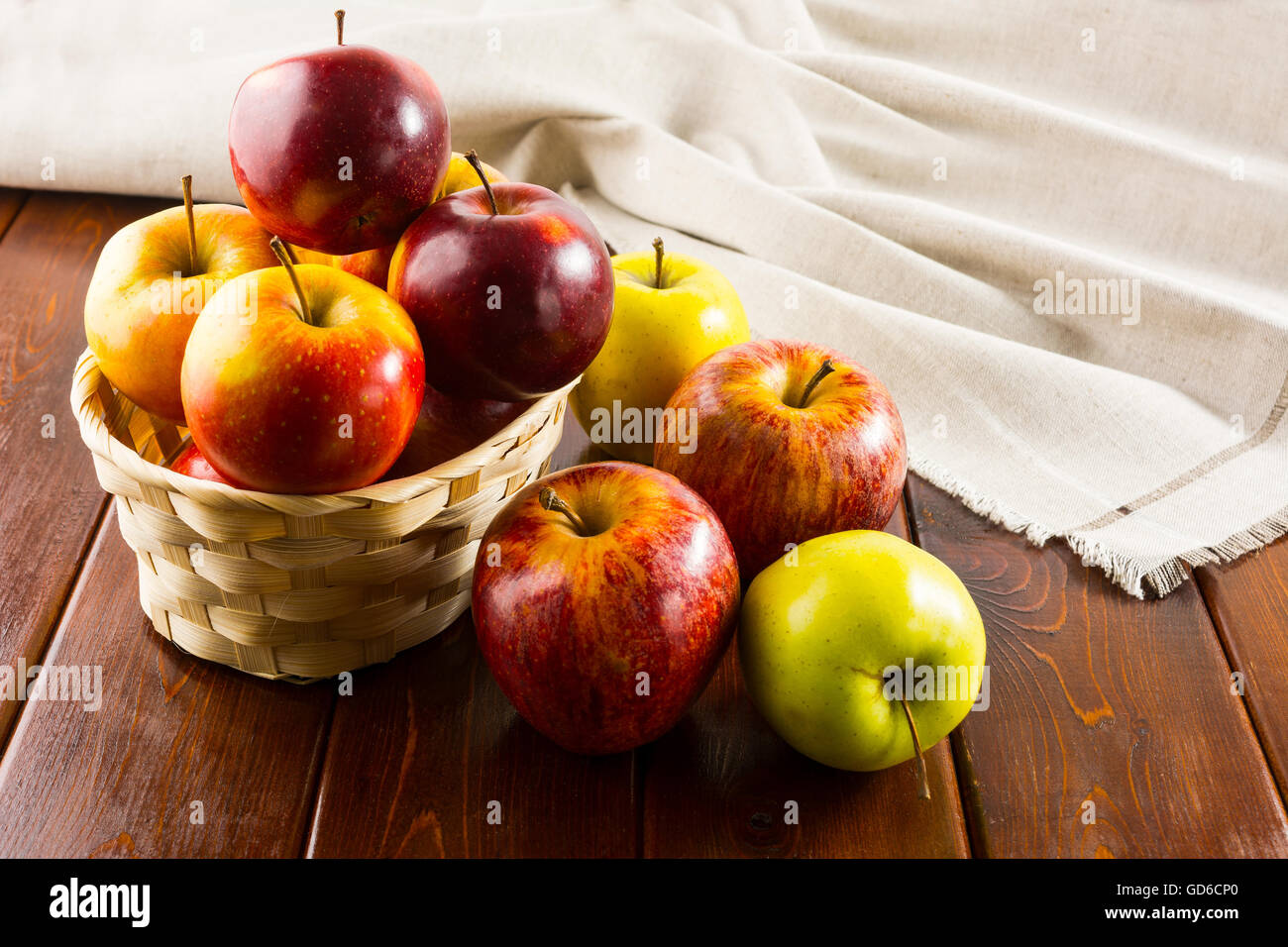 Le mele nel Piccolo cesto di vimini sul legno scuro dello sfondo. Mangiare sano concetto con frutta fresca. Foto Stock