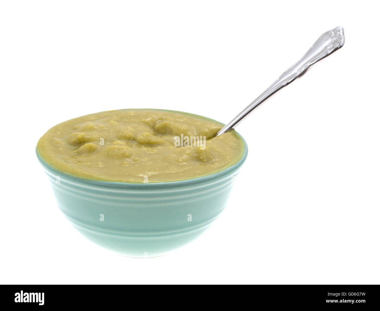Una ciotola di verde spessa zuppa di piselli quasi traboccare con un cucchiaio inserita nel cibo isolato su uno sfondo bianco. Foto Stock