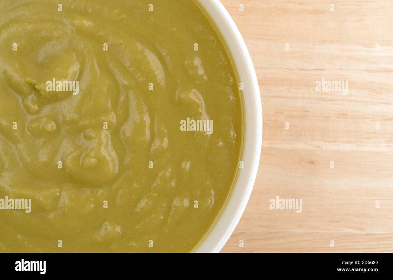 Top vista ravvicinata di una ciotola di verde spessa zuppa di piselli su una tavola di legno alto. Foto Stock