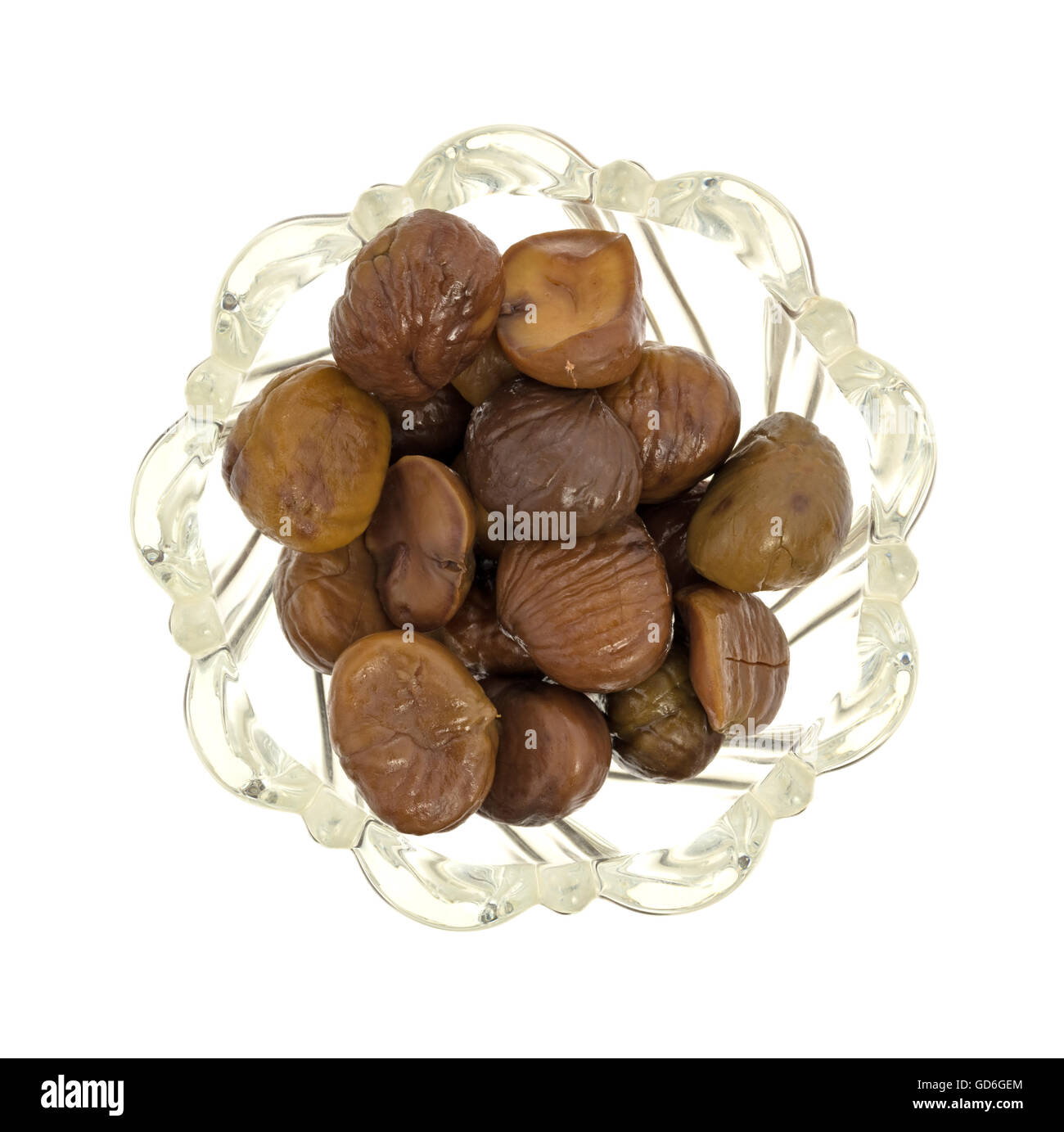 Vista dall'alto di una ciotola di vetro riempito con organici intere sgusciate castagne arrostite isolato su uno sfondo bianco. Foto Stock