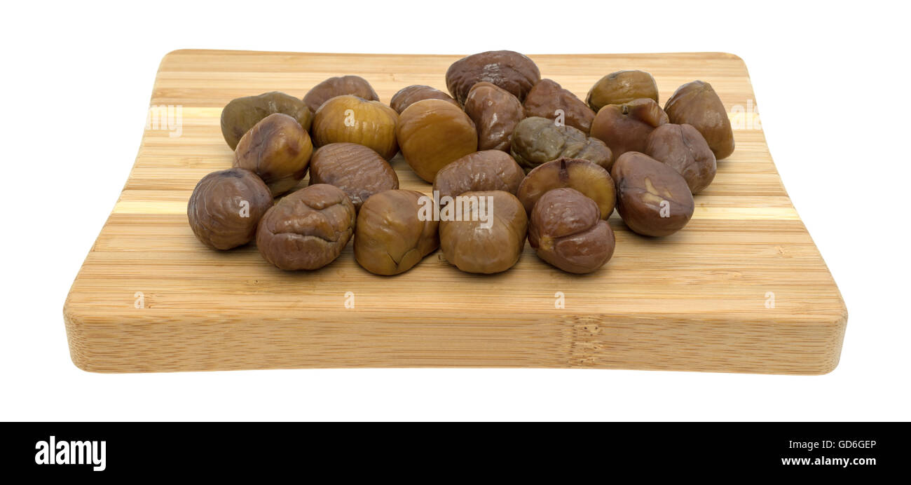 Organici di intere sgusciate castagne arrostite su un legno tagliere isolato su uno sfondo bianco. Foto Stock