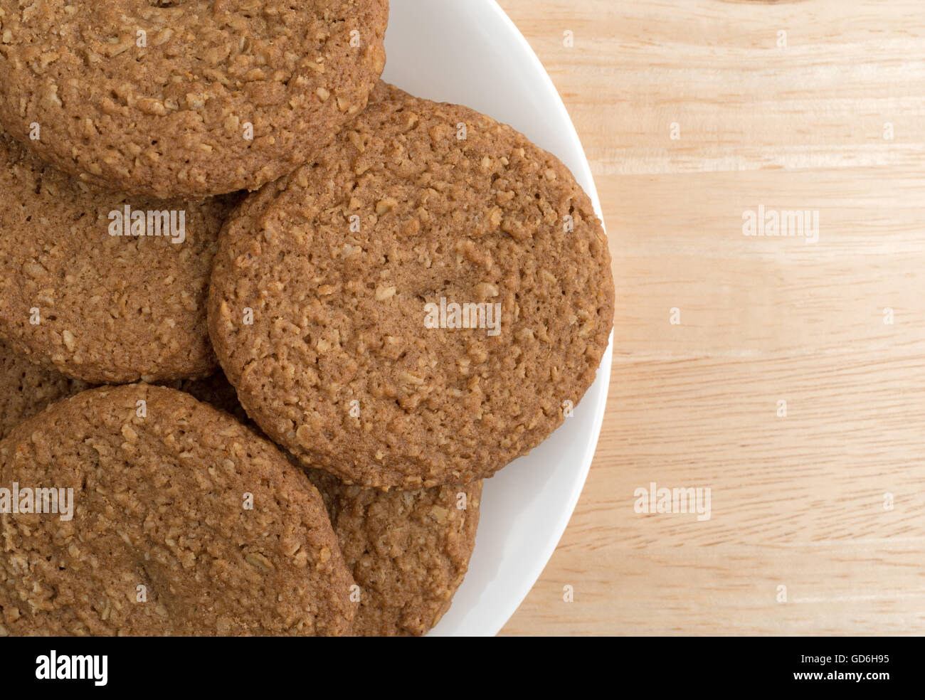 Top vista ravvicinata di una piastra di fiocchi d'avena zucchero libero i cookie su una tavola di legno alto. Foto Stock