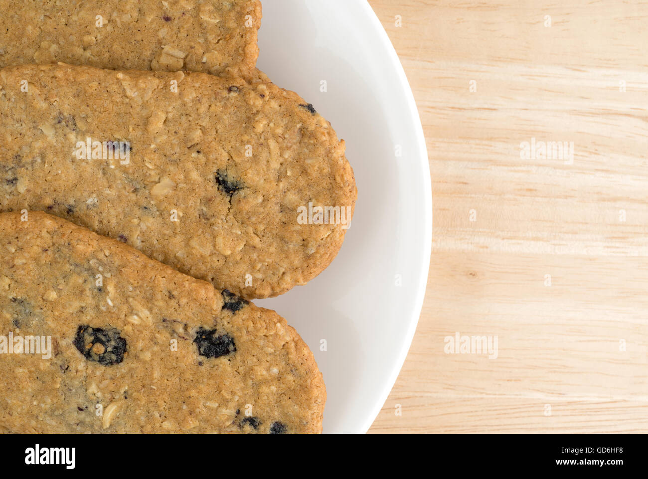 Top vista ravvicinata di mirtillo fetta i cookie su una piastra bianca in cima a una tavola di legno alto. Foto Stock