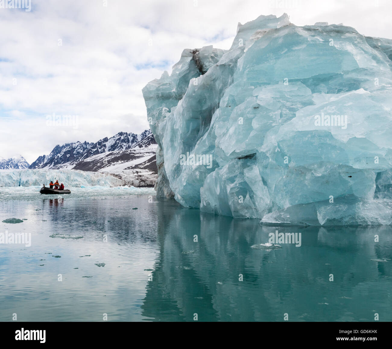 Blu iceberg torreggia su zattera gonfiabile, Liefdefjorden, Svalbard, Norvegia. Monacobreen (Monaco glacier) è visibile dietro. Foto Stock