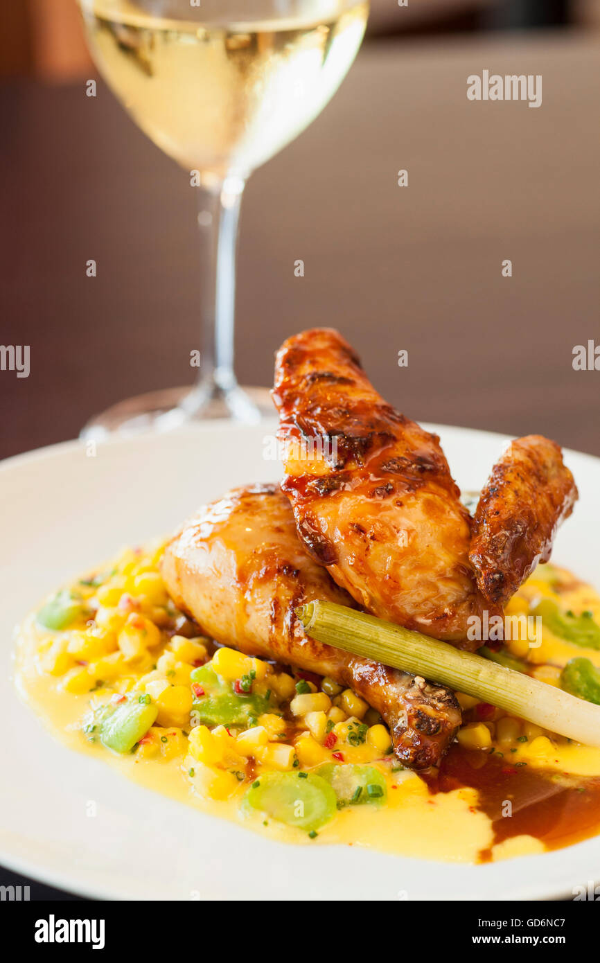 Mezza Mary's free range chicken over succotash con un bicchiere di vino chardonnay, Nuance Ristorante Santa Barbara, California Foto Stock