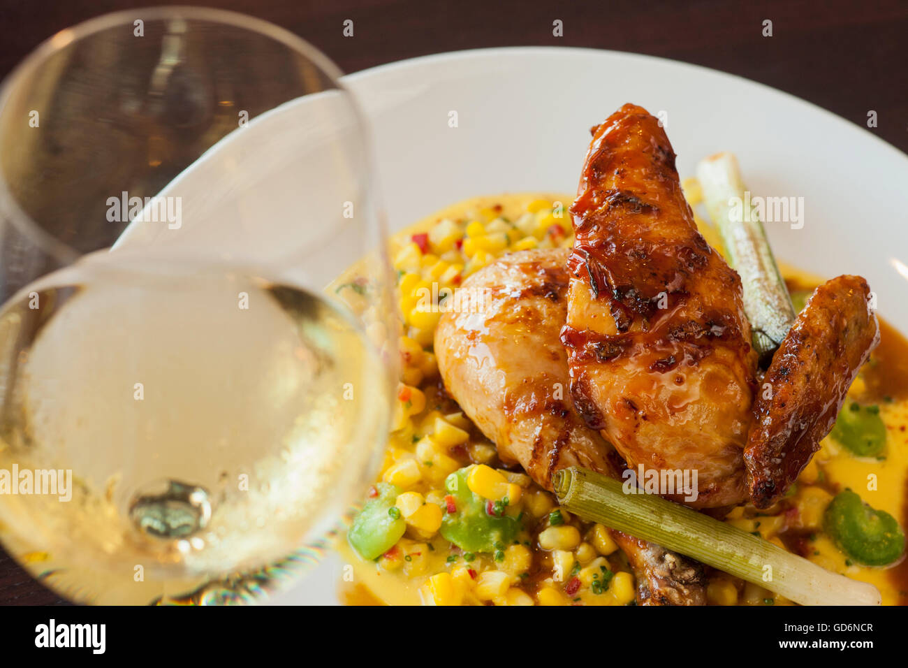 Mezza Mary's free range chicken over succotash con un bicchiere di vino chardonnay, Nuance Ristorante Santa Barbara, California Foto Stock