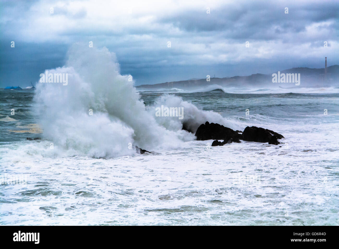 Vista panoramica del mare agitato con spruzzi d'onda rocce contro le nubi Foto Stock