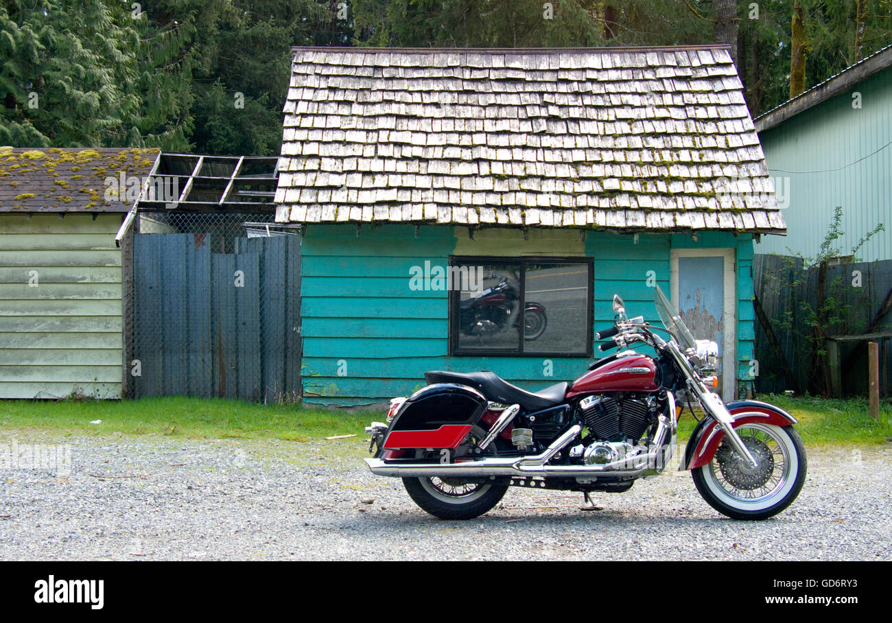 Un bel color mirtillo palustre di stile cruiser motociclo è parcheggiata di fronte a shingle con tetti color turchese cabina. Foto Stock
